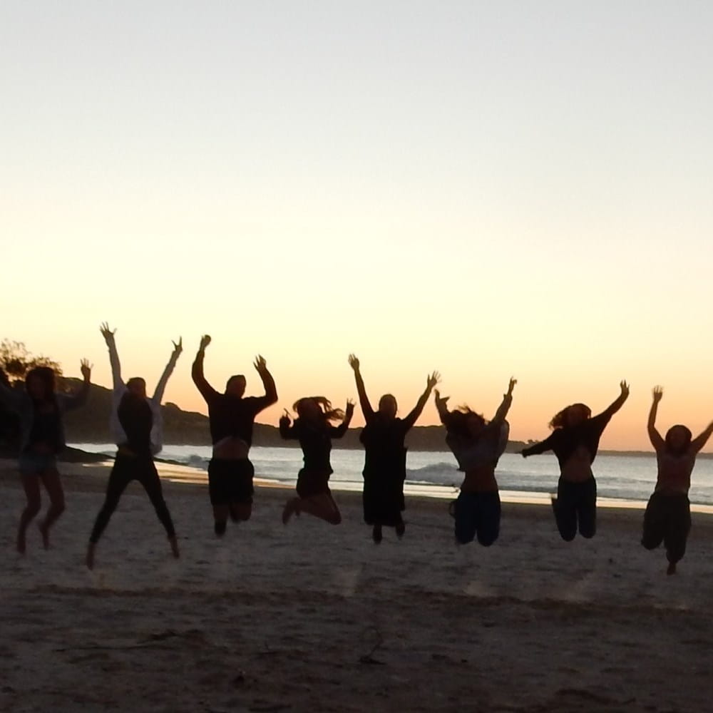 People on a beach jumping in front of sunset