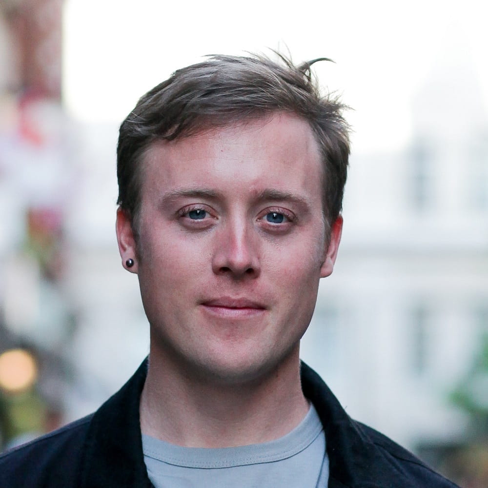 A head and shoulders shot of William McCallam, with an out of focus building in the background.