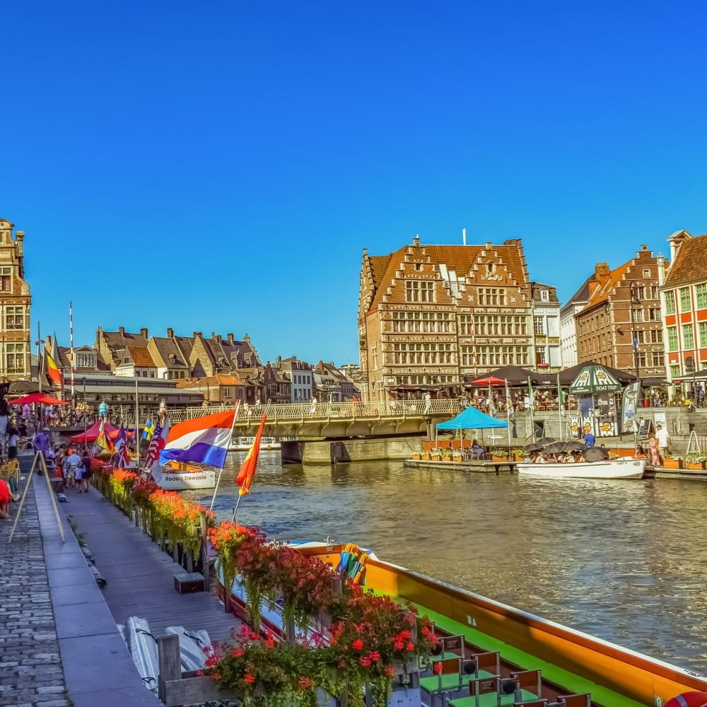 A river in the centre of Ghent, with a bridge crossing over the water and old buildings in the background.