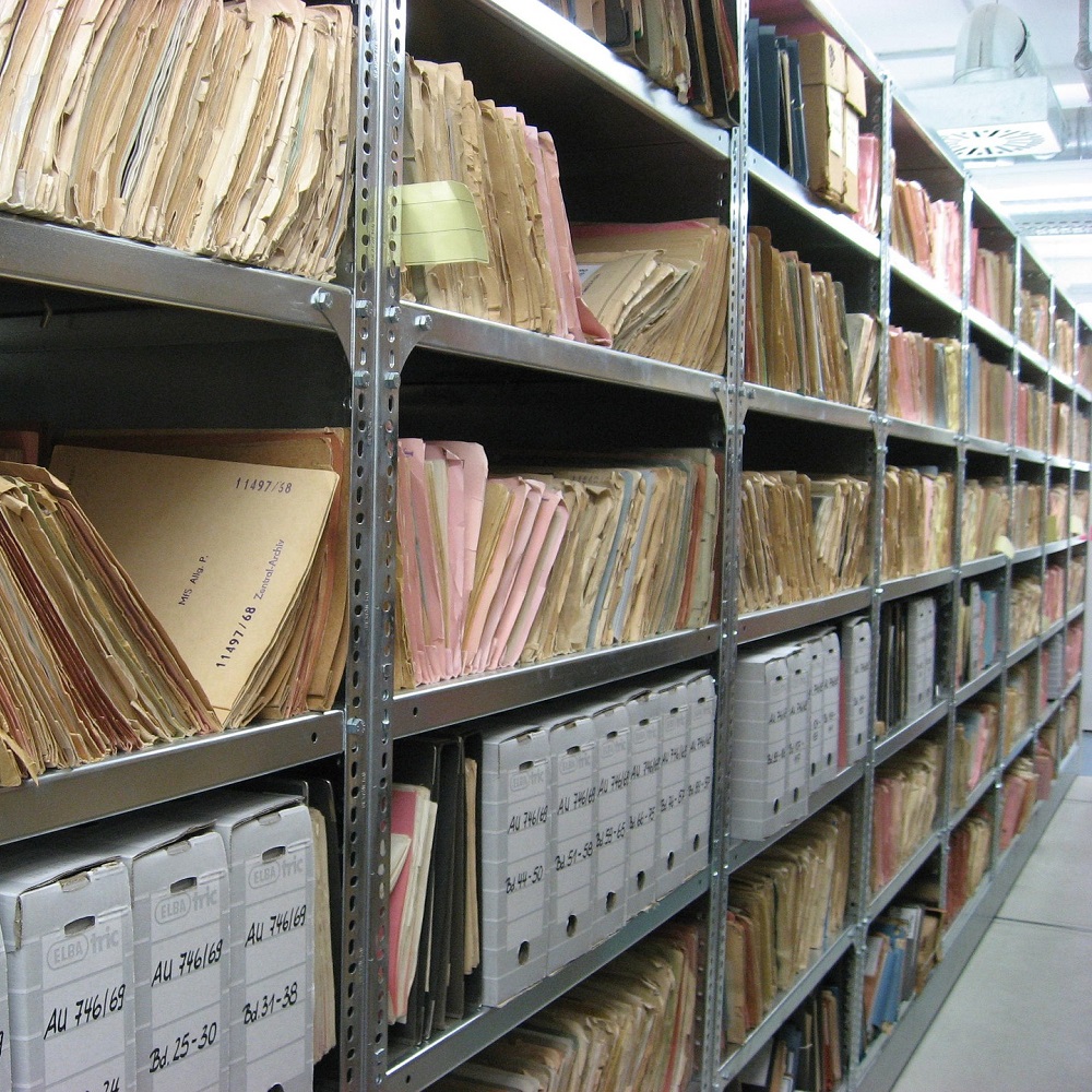 Racks of metal shelving covered in folders and white boxes.