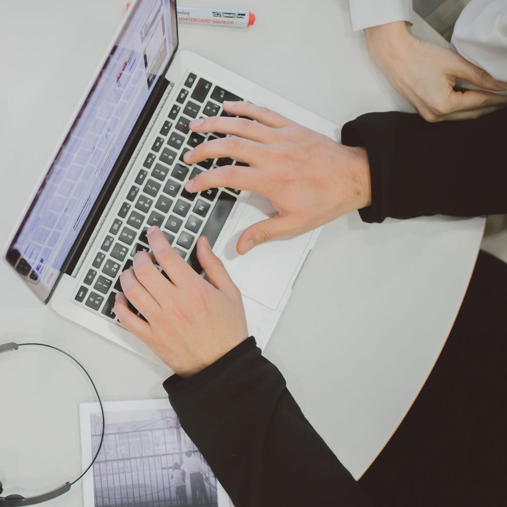 A pair of hands poised over the keyboard of a laptop.