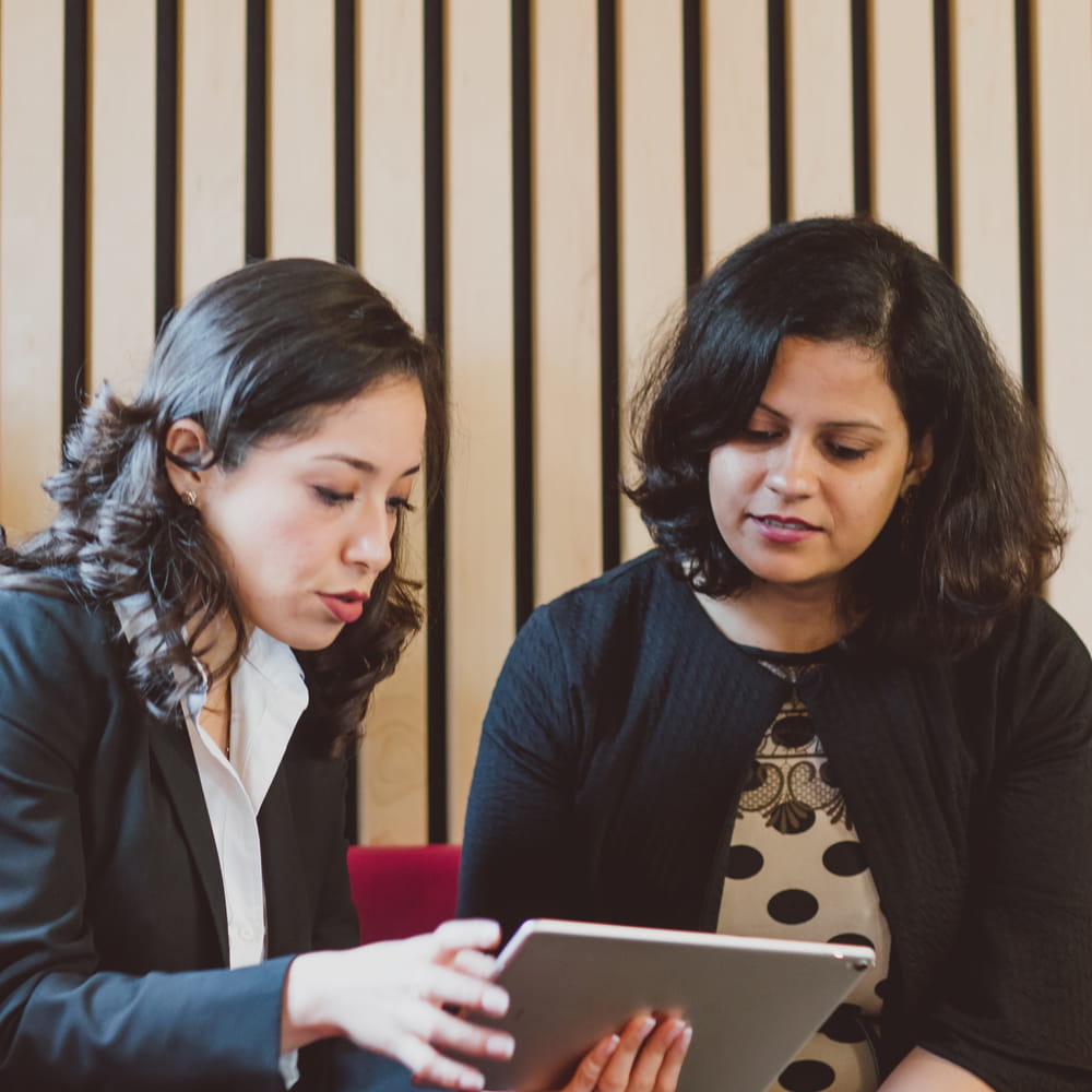Two female students discussing ideas at an ipad 
