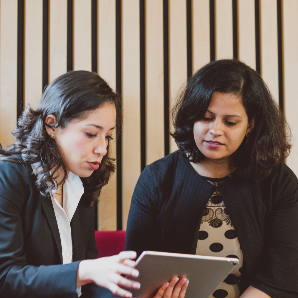 Two female students discussing ideas at an ipad 
