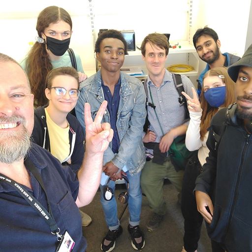 Professor Reinhold Scherer, making a "peace" sign with one hand, taking a selfie with his team.