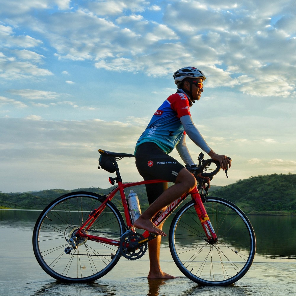 A cyclist on a bike next to a lake.
