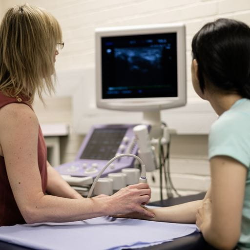 Two people looking at a screen showing an ultrasound image of a wrist