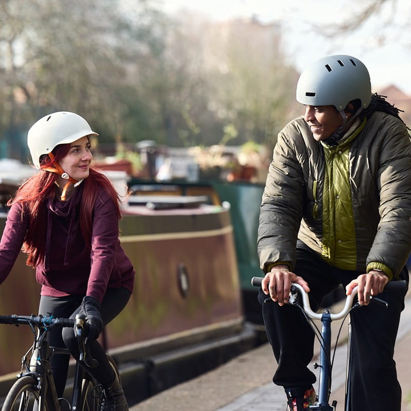 Two people cycling, with canal boats in the background.
