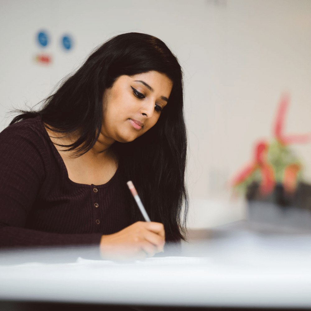 Girl with dark hair writing notes on a piece of paper