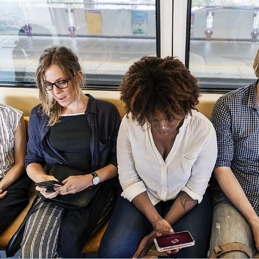 Two women sat on a train texting on their phones