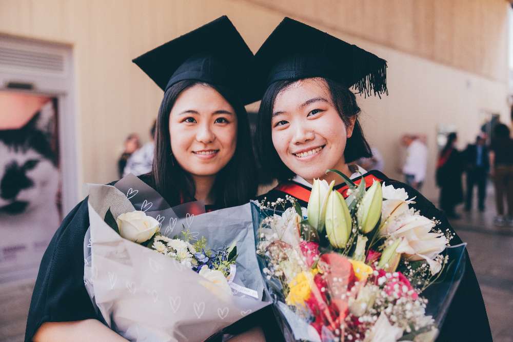 Two graduating students with flowers