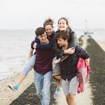 Students giving each other a piggy back on the beach