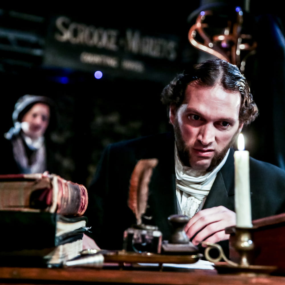 Scrooge at a desk in A Christmas Carol