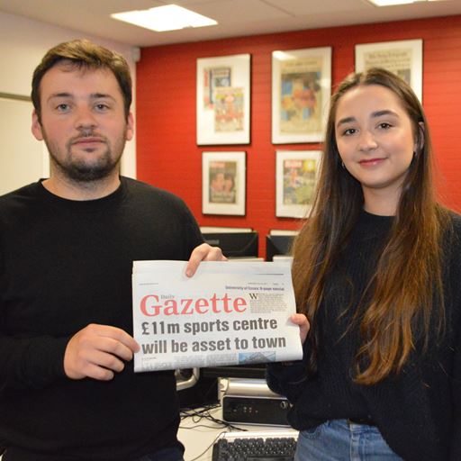 Two journalism students holding up a newspaper