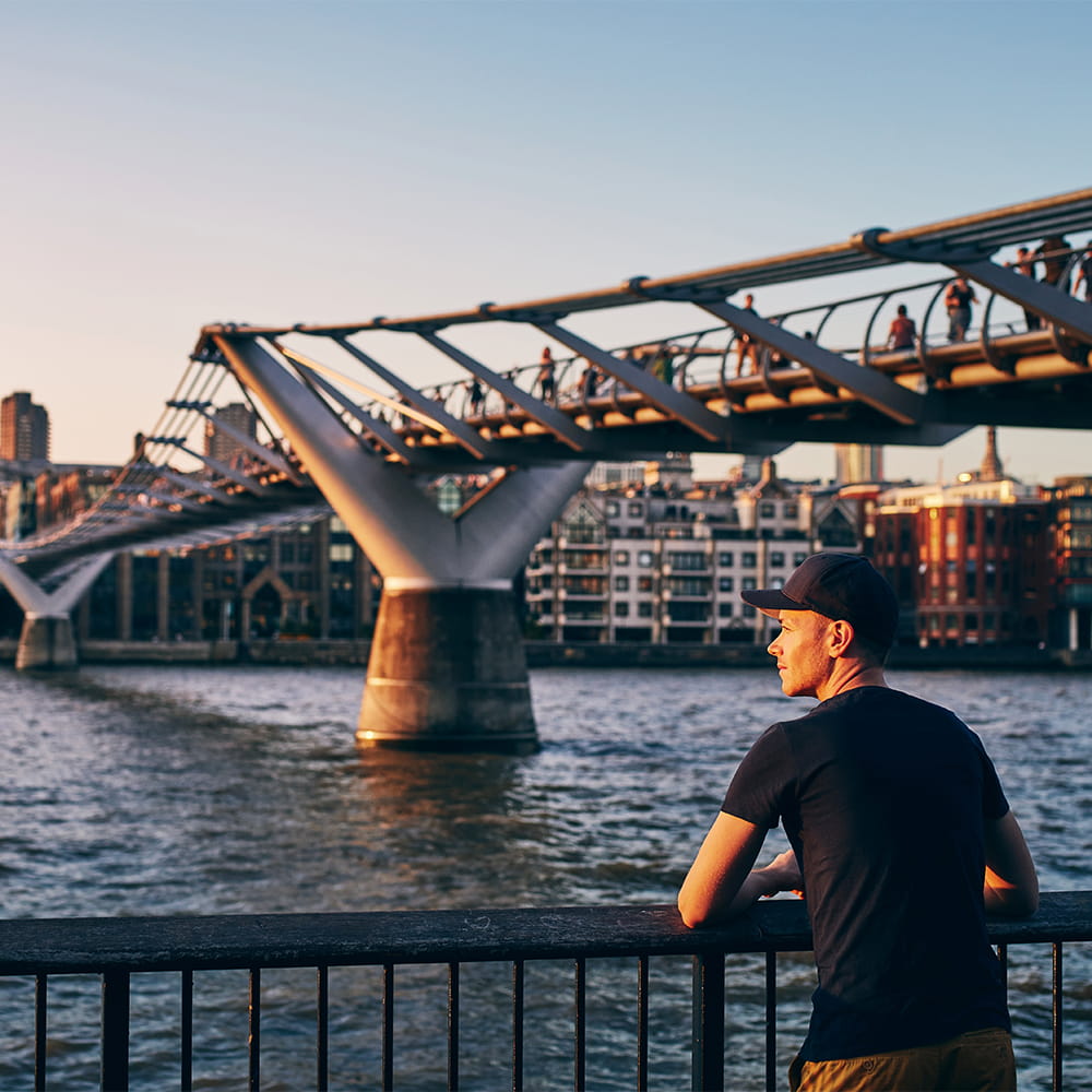 Young adult overlooking river thames with sun setting on him