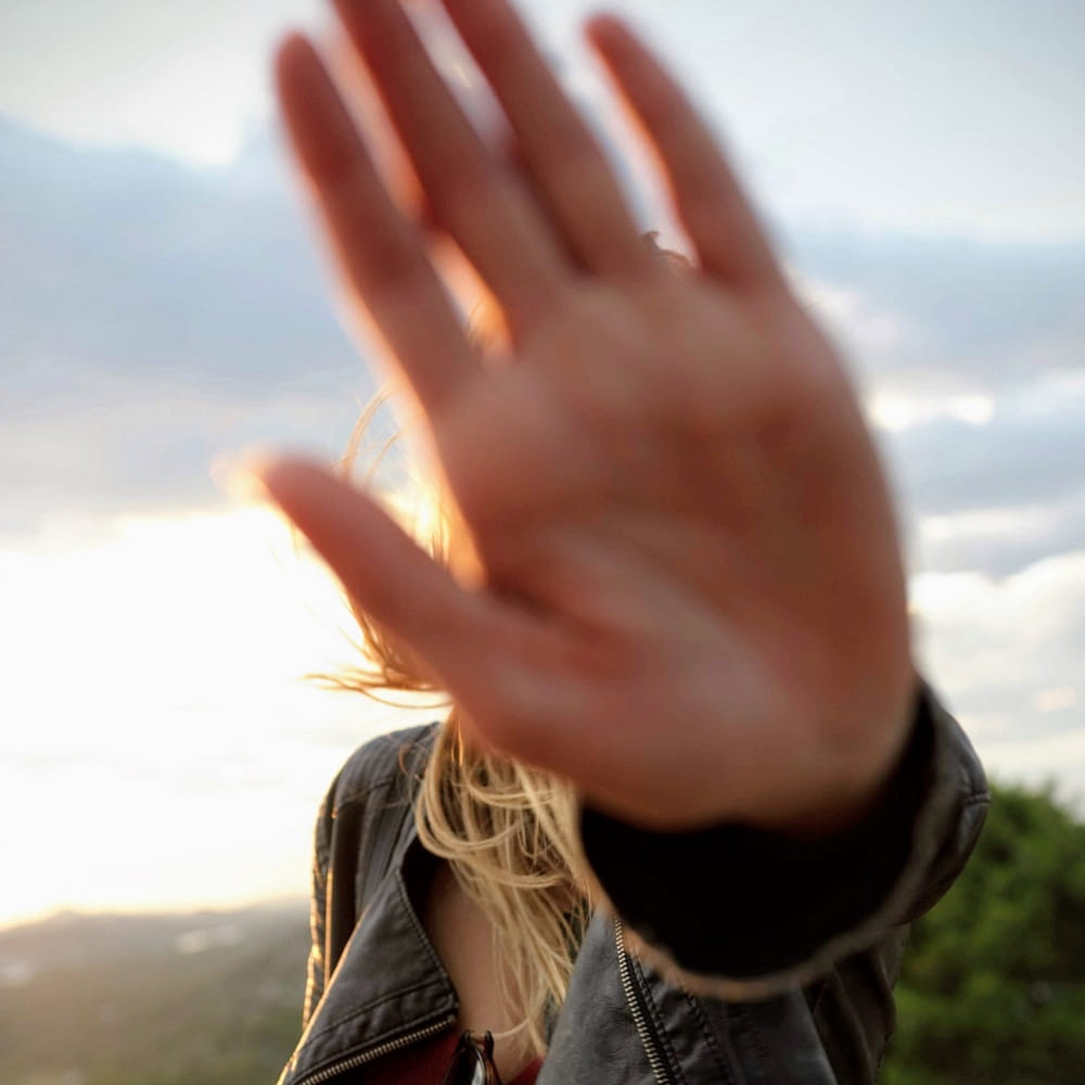 Woman holding up her hand in front of her face.