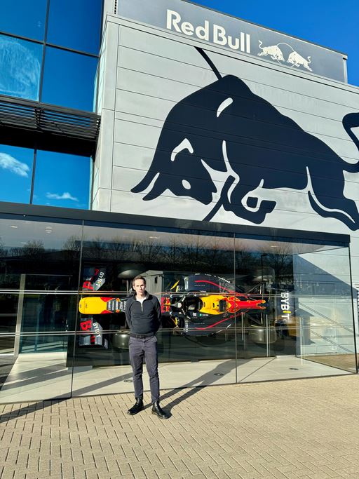 Martin Galpin standing in front of Red Bull glass building with a sports car behind him