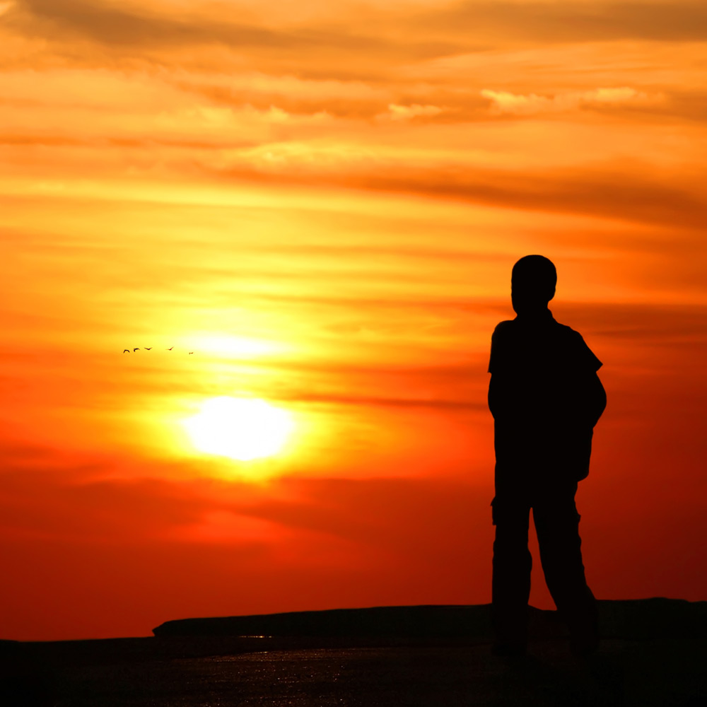 Photo of person gazing out towards a sunset