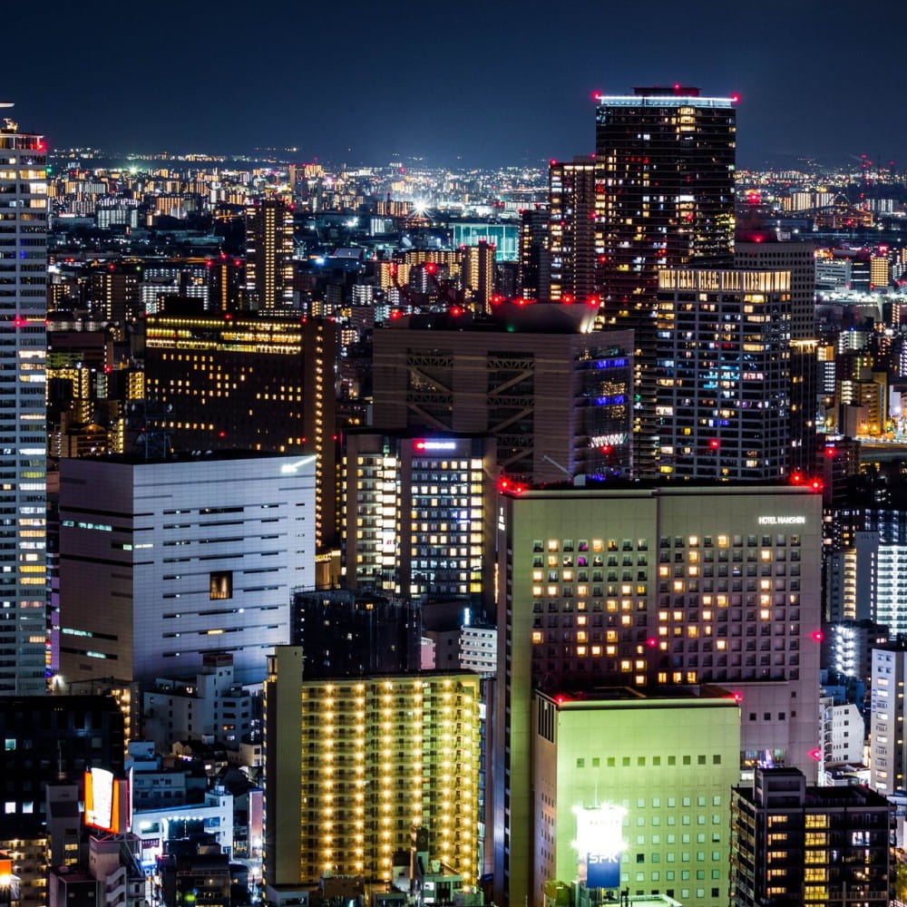 The skyline of the city of Osaka at night, with the city lit up.