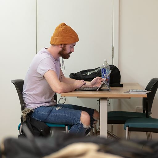 An Essex Business School student sits in a study pod with his laptop in the business school building