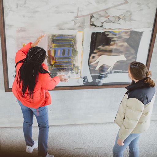 Students examining a piece of art hung on the wall