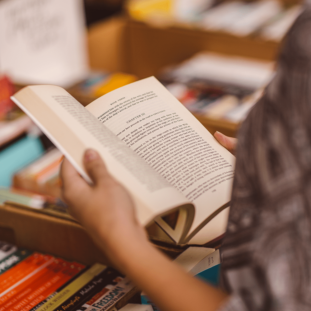 A close-up of a student reading a book at a book sale.