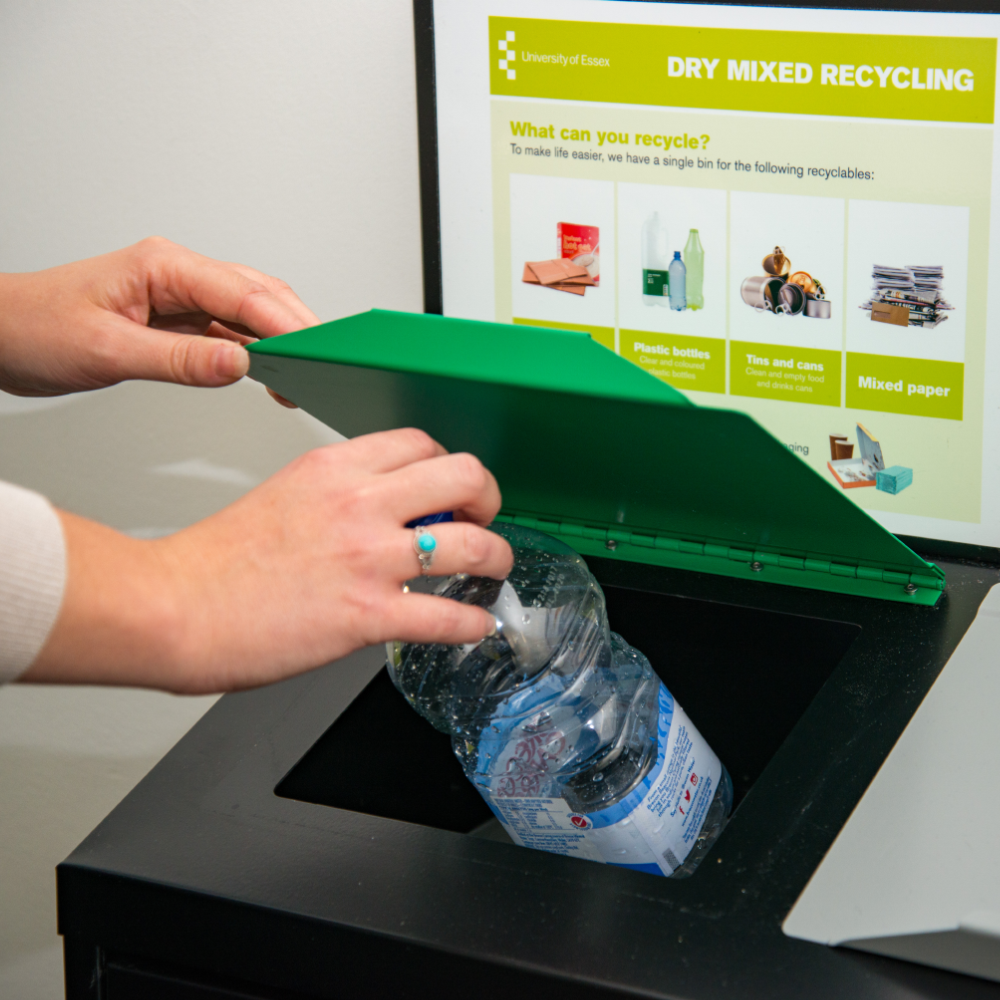 Image of someone putting a plastic bottle in the dry mixed recycling bin.