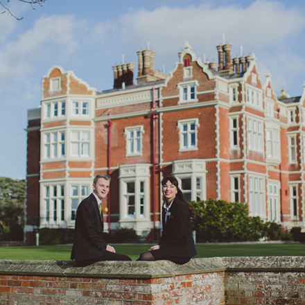 Two Edge Hotel students sitting in front of Wivenhoe House Hotel
