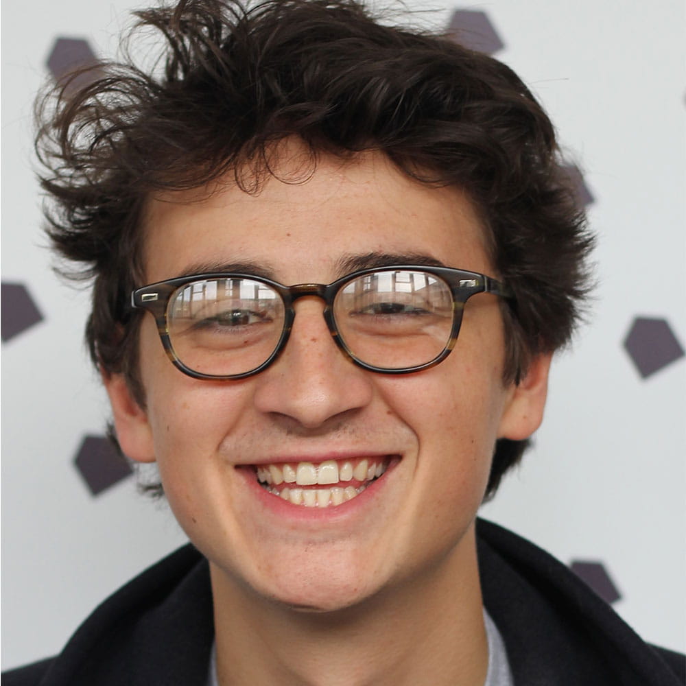 Tanki, wearing glasses, smiling straight towards the camera