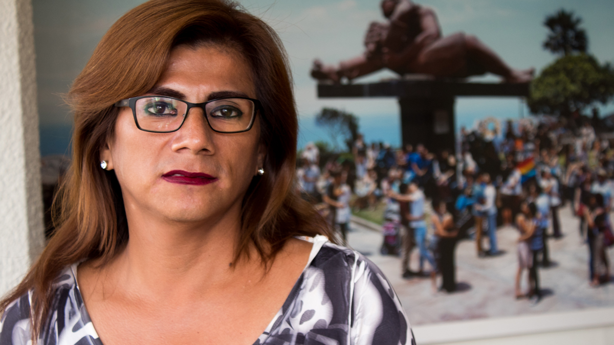 Azul Rojas Marín, a woman in glasses, is standing in front of a picture of a national monument
