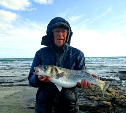 Mike profile picture holding bass in front of a sea view