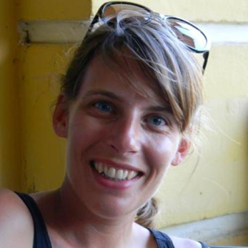 Woman smiling for a profile picture with her head tilted to the right and glasses on her head