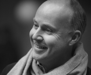 A black and white image of David. He is wearing a scarf and looking in another direction