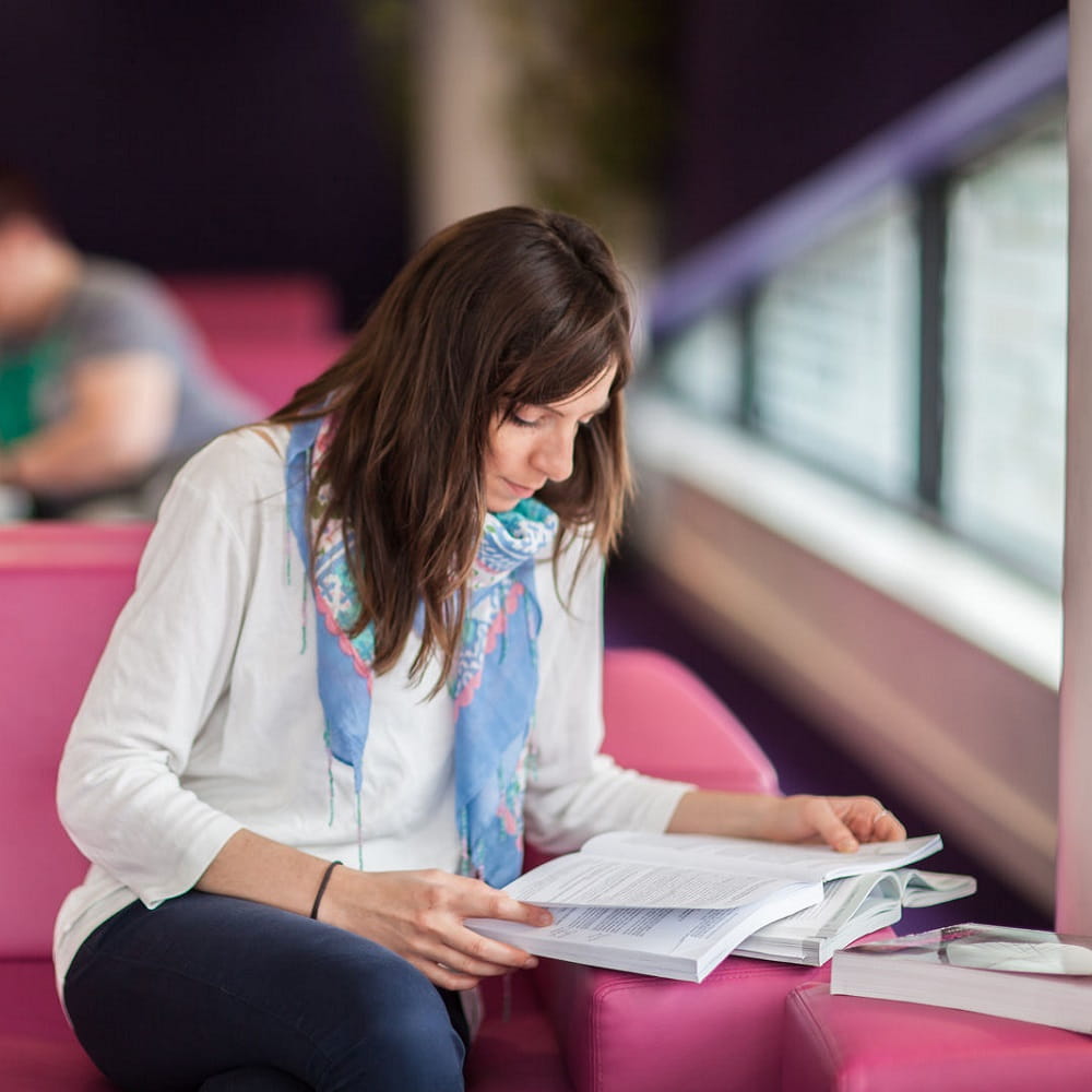 student sitting reading book on sofa