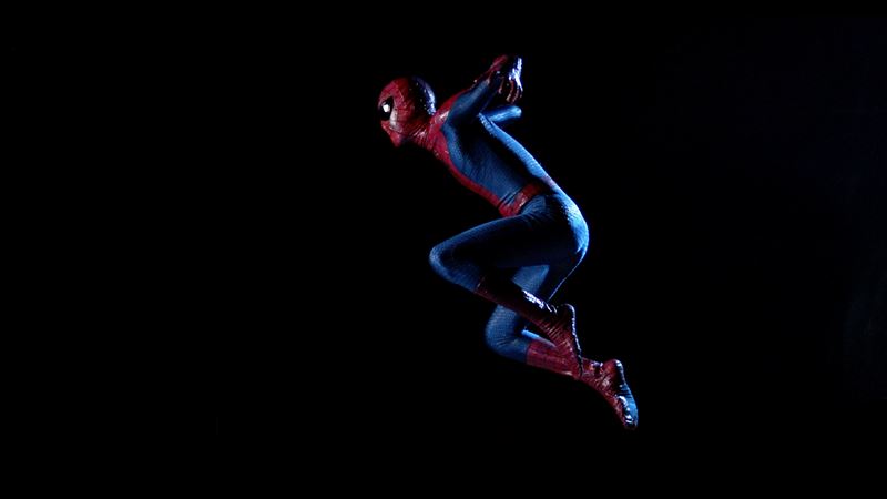 A still from Hetain Patel's award-winning film, The Jump, which features the artist dressed as Spiderman in mid-jump on a black background.