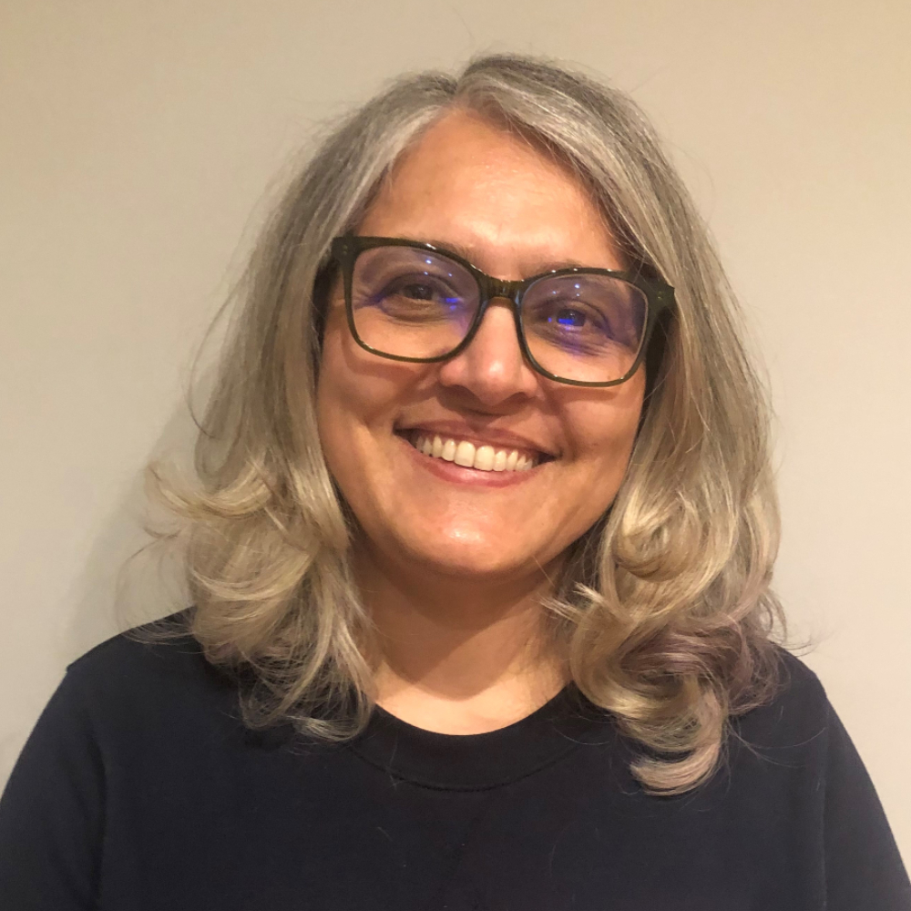 Professor Camille Cronin, wearing glasses and smiling directly at the camera.