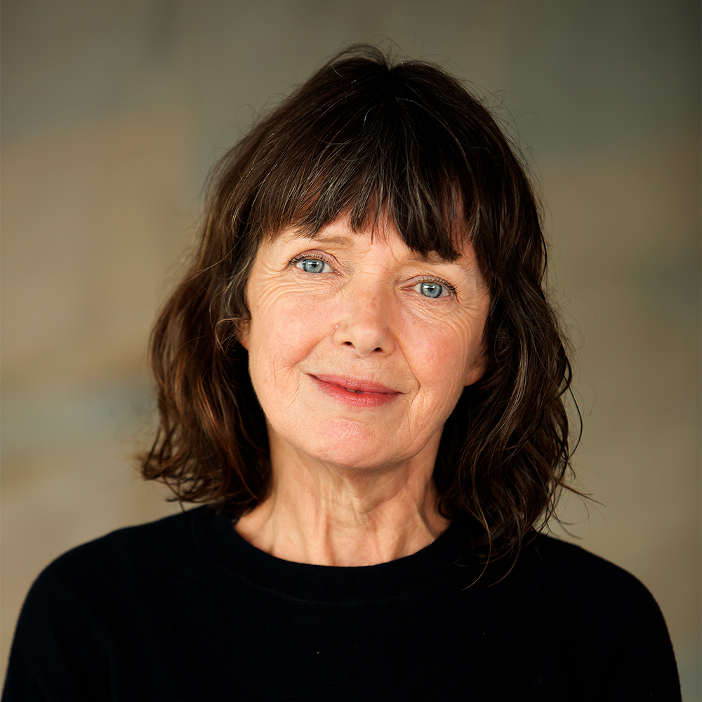 Jess Twyman, Curator of Art Exchange stands in the Silberrad Student Centre wearing a black jumper and mid-length cropped brown hair.