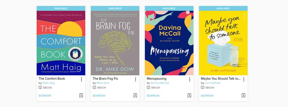 A screenshot of the Overdrive wellbing collection of ebooks and auidobooks. The screenshot shows a selection of four books from the collection: "The Comfort Book" by Matt Haig, "The Brain Fog Fix" by Dr. Mike Dow, "Menopausing" by Davina McCall and "Maybe You Should Talk to Someone" by Lori Gottlieb.