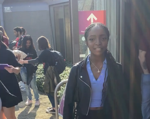 BSc Management and Marketing student, Natasha Ezeh, stands outside the Essex Business School building on a busy and sunny day.