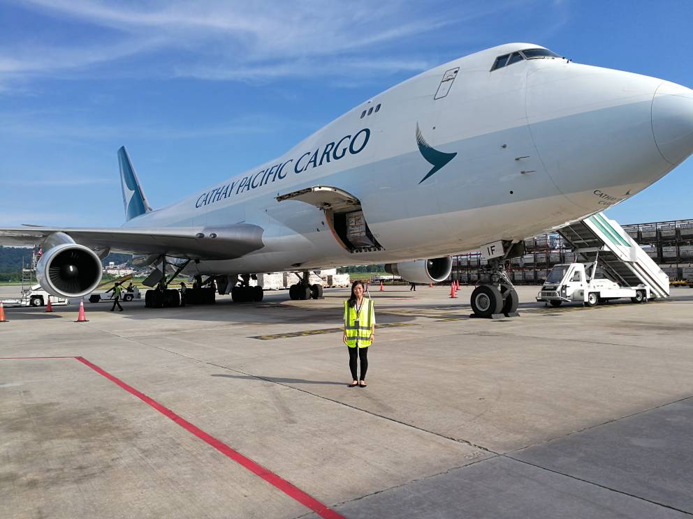 Koo Kah Ming working for Expeditors stood in front of a large passenger jet in high vis