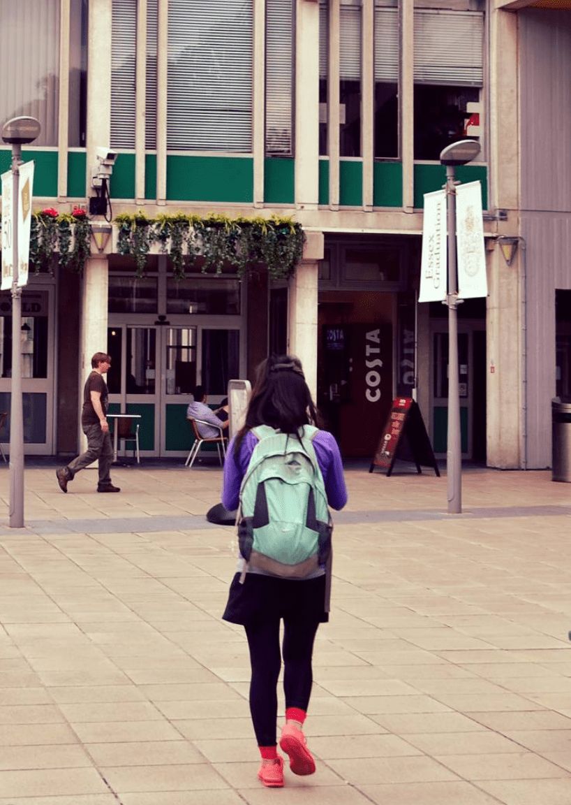 Student wearing a rucksack walking across Square 3