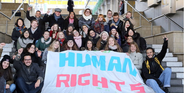 Human Rights students sitting on the Square 3 steps with Human Rights banner