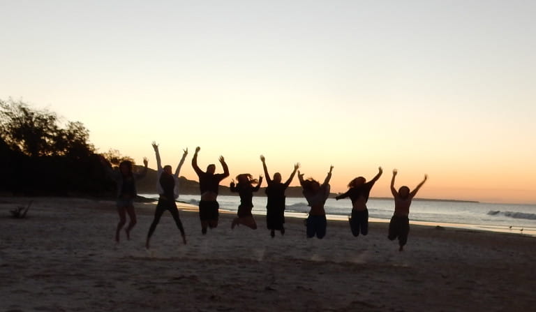Silhouette of a group of people jumping on a beach at sunset