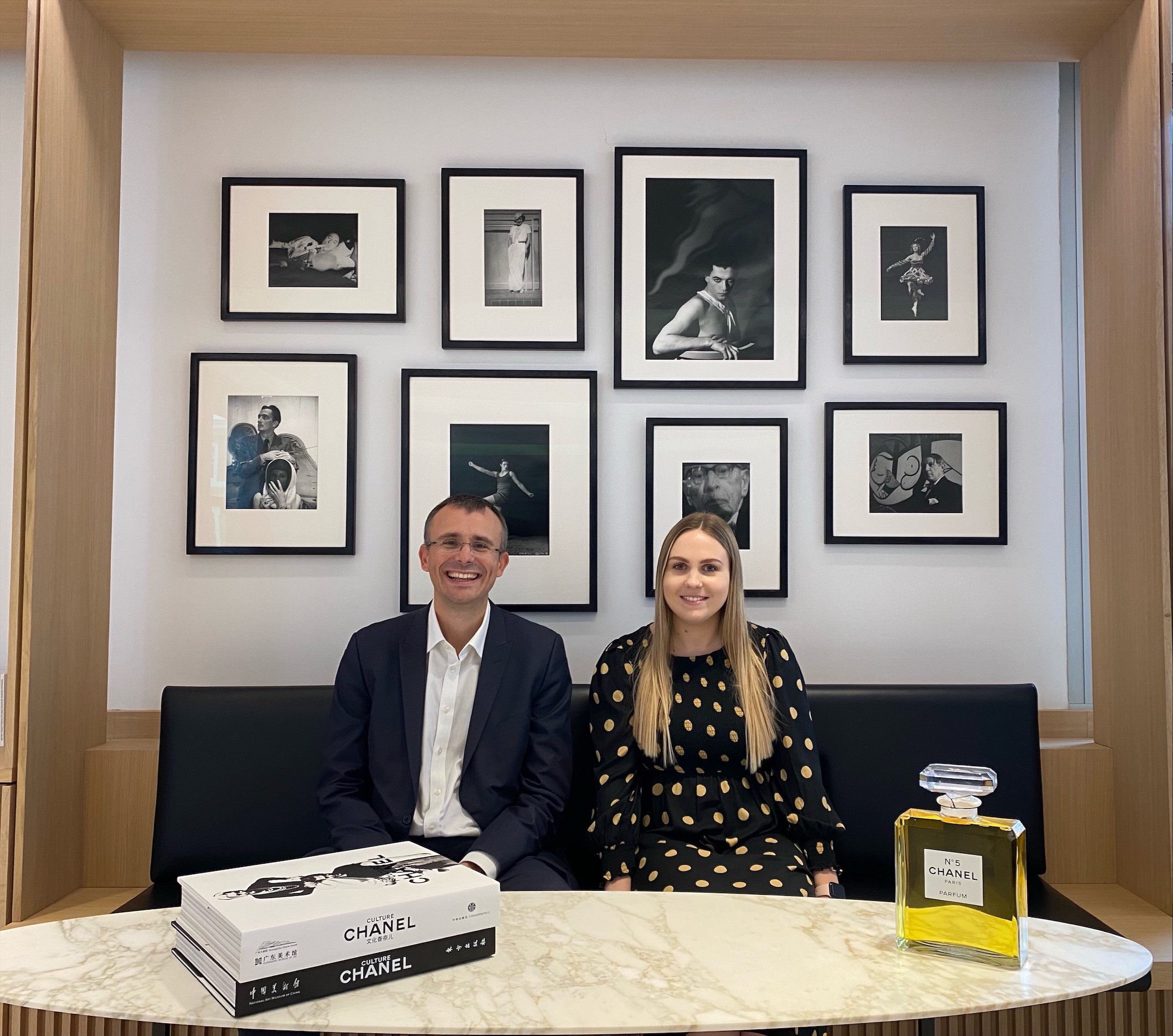 Essex graduates Steve and Charlotte sat together in their office with numerous pieces of Chanel merchandise