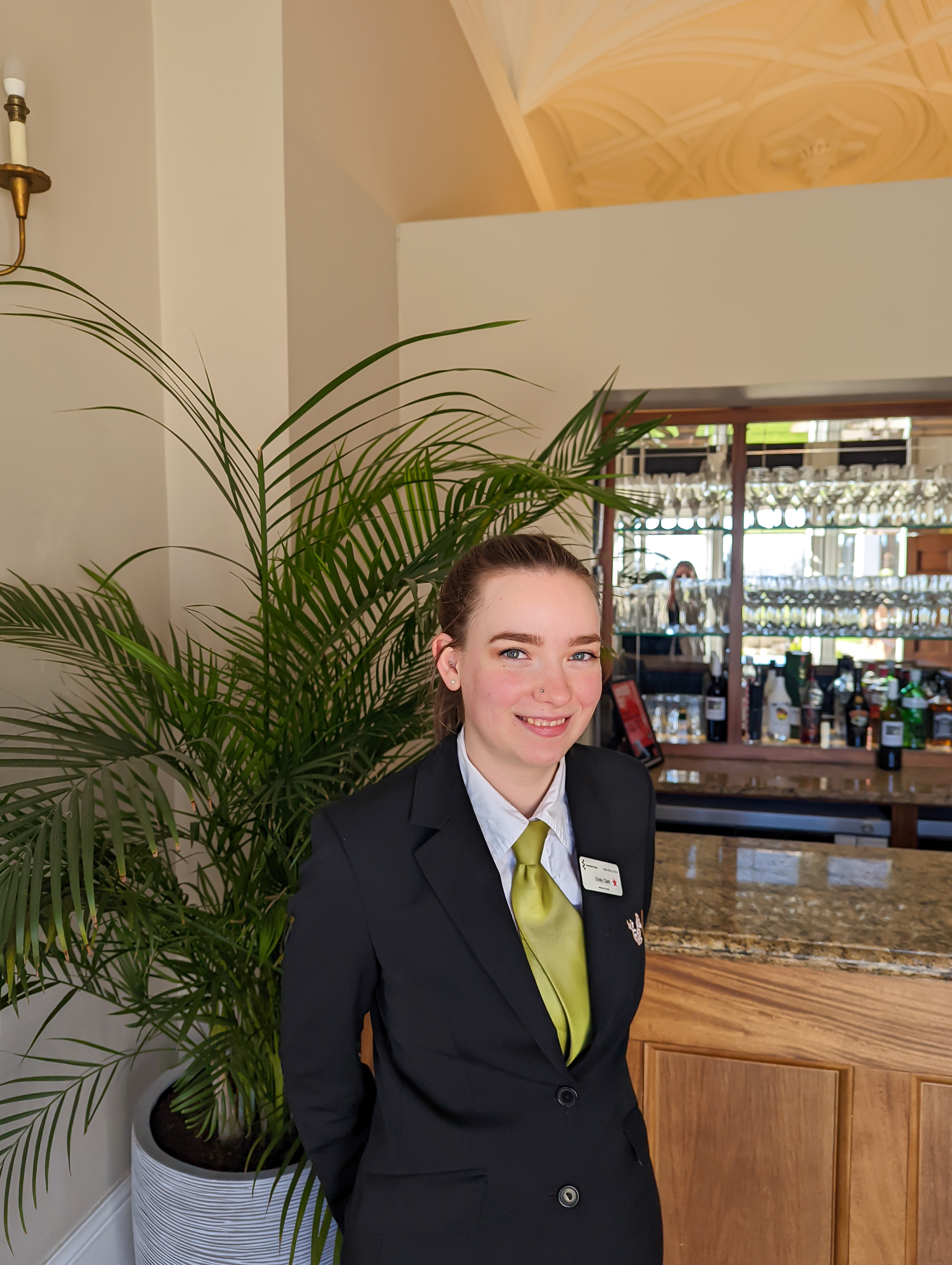Student in Edge Hotel School uniform stood in front of a bar