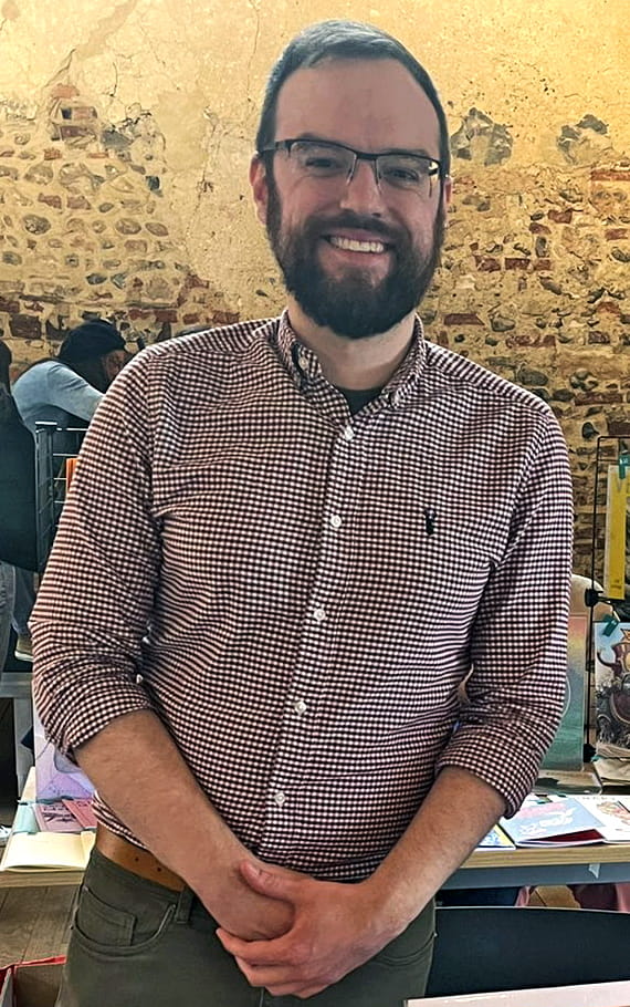 Simon is standing with hands crossed and smiling at the camera