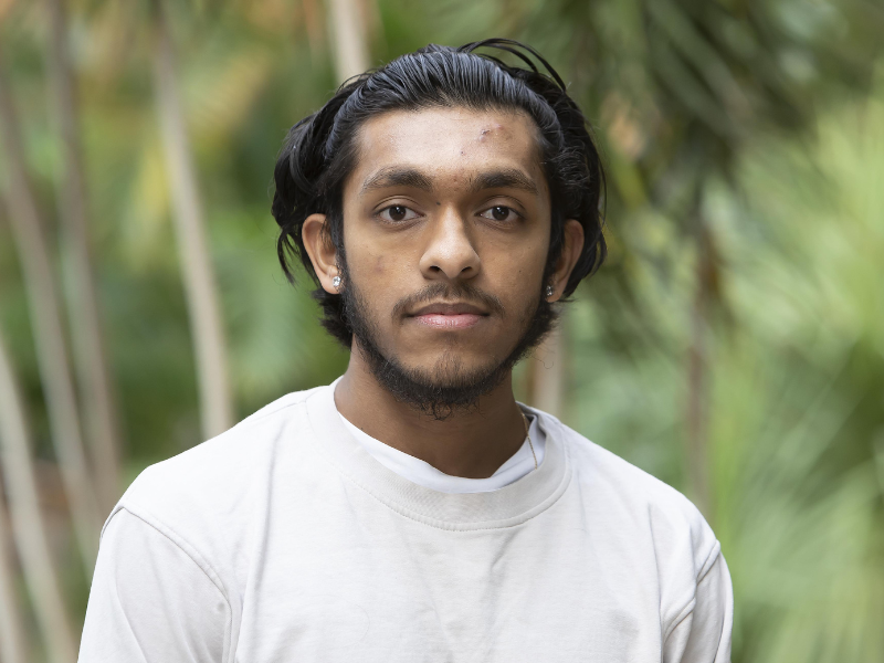 A headshot of student Neil Chamroo with plants in the background