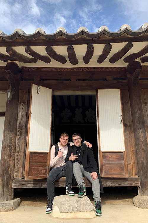 two students sitting on the steps of a house in Korea