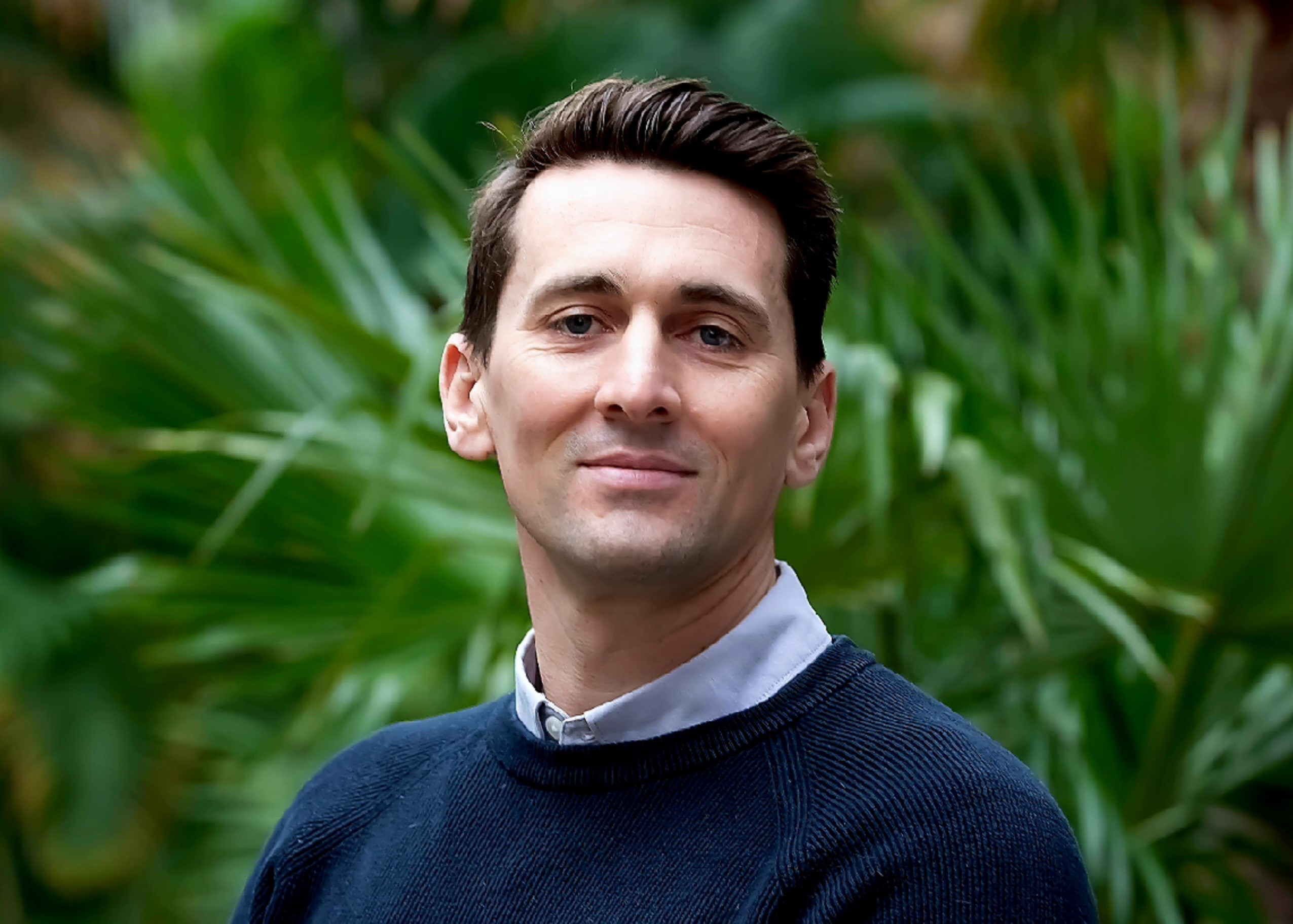Daniel Smart standing in front of a background of foliage in formal wear