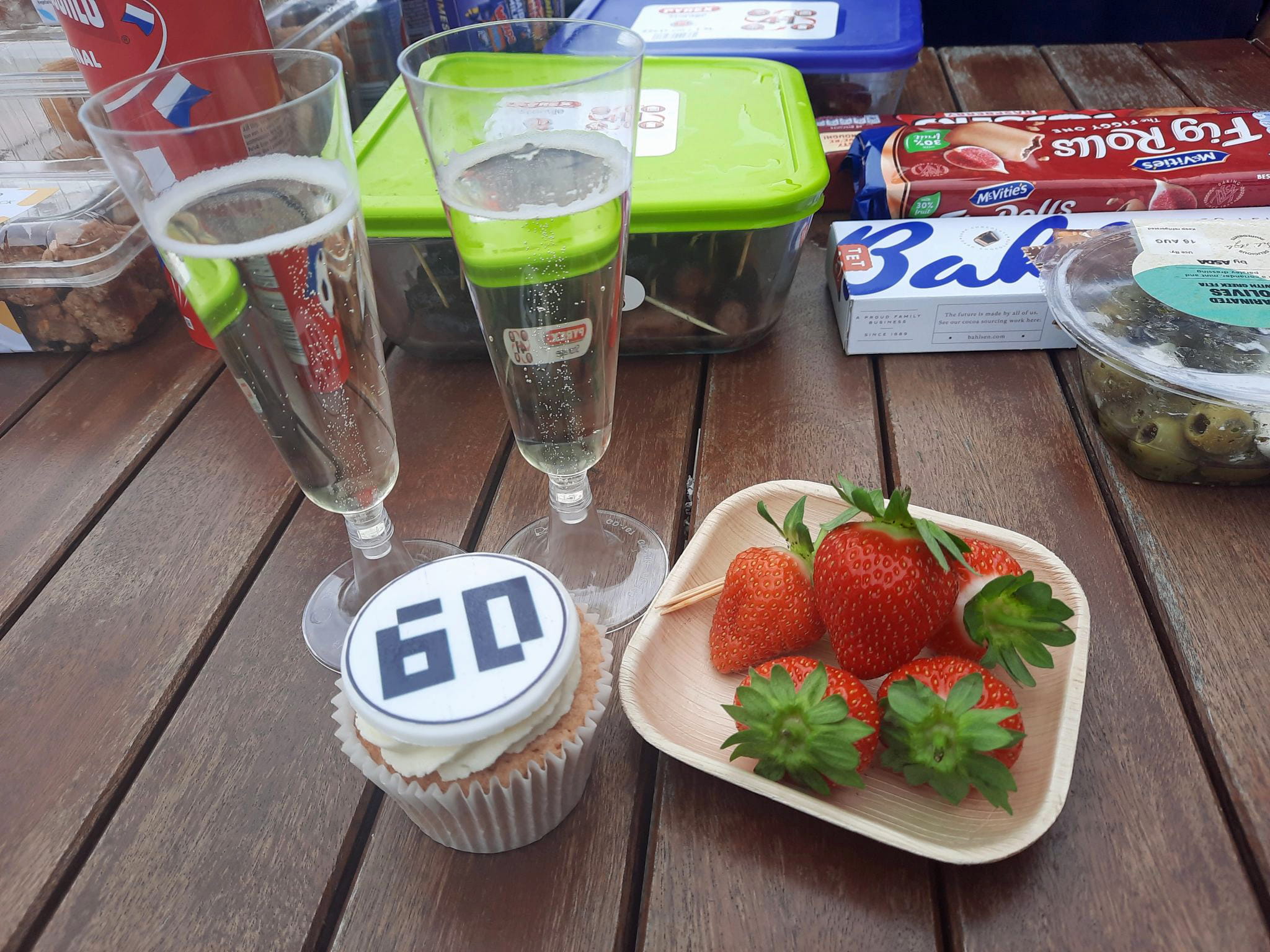 A table laden with snacks including strawberries and cakes.