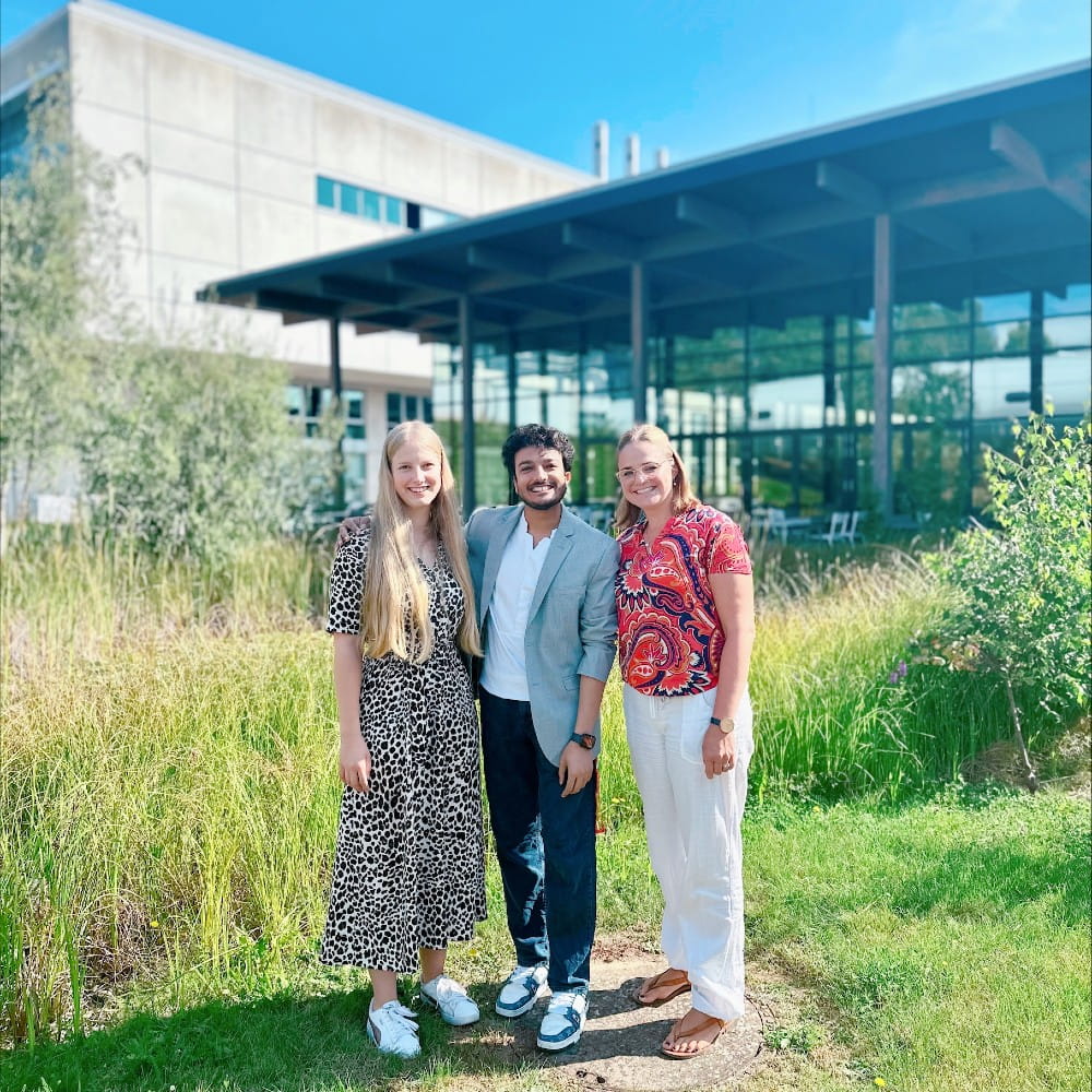3 people stand in front of an office space smiling